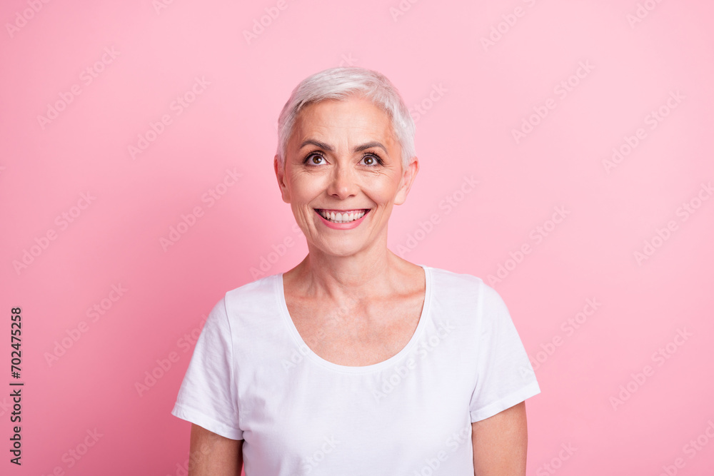 Photo portrait of pretty retired female look up empty space billboard dressed stylish white outfit isolated on pink color background Photo portrait of pretty retired female look up empty space billboard dressed stylish white outfit isolated on pink color background
