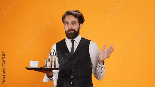 Restaurant butler acting surprised on camera, being in shock after finding news in studio. Man fine dining employee feeling shocked and carrying food and drink tray at clients table. photo