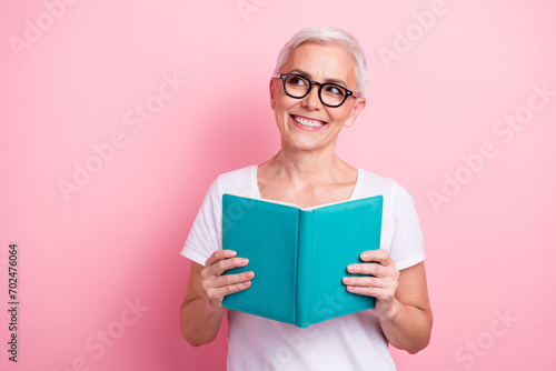 Portrait of toothy beaming person with white hairdo dressed stylish t-shirt read book look at sale empty space isolated on pink background