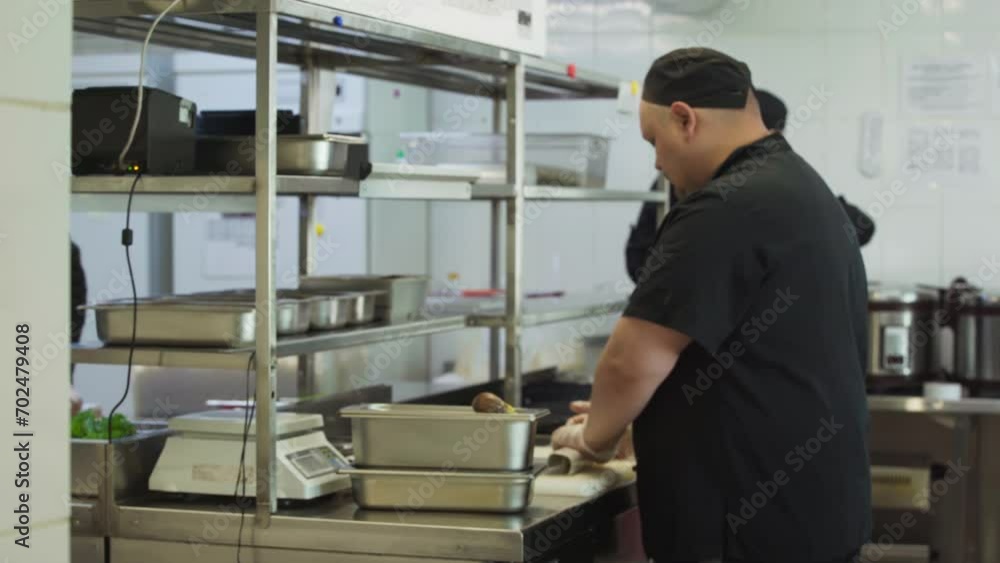 Kitchen cook is using rolling mat for sushi preparation in Japanese cuisine restaurant. Cooking delicious sushi in restaurant kitchen. Sushi roll preparation process in the Japanese restaurant kitchen Kitchen cook is using rolling mat for sushi preparation in Japanese cuisine restaurant. Cooking delicious sushi in restaurant kitchen. Sushi roll preparation process in the Japanese restaurant kitchen