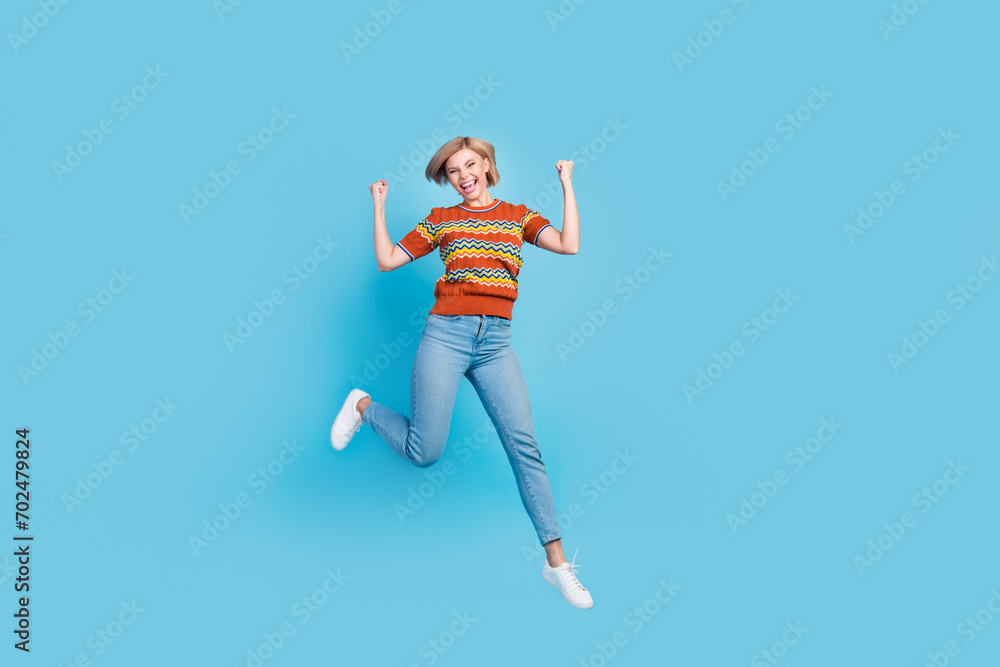 Full length photo of crazy ecstatic girl wear strited t-shirt jeans flying scream yeah win lottery isolated on blue color background