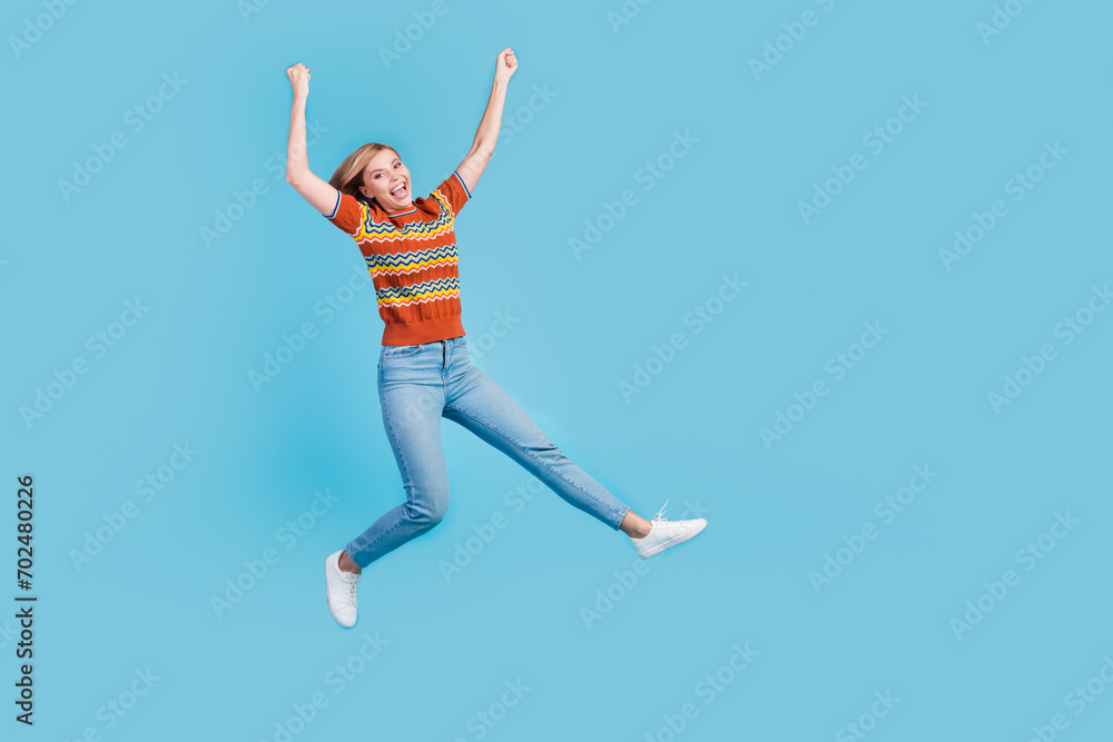Full length photo of optimistic girl wear strited t-shirt jeans flying hands up celebrate balck friday isolated on blue color background