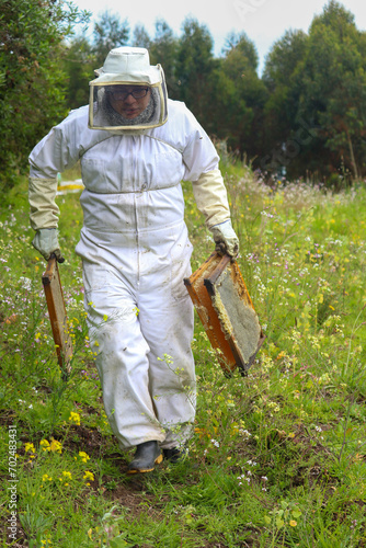 apicultor llevando unos panales de abejas en ambas manos en medio del campo  photo