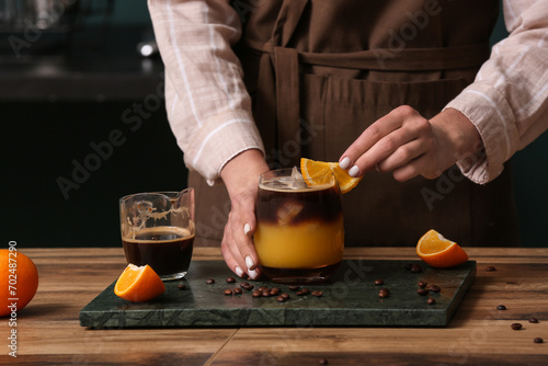 Female barista with glass of coffee drink at table, closeup