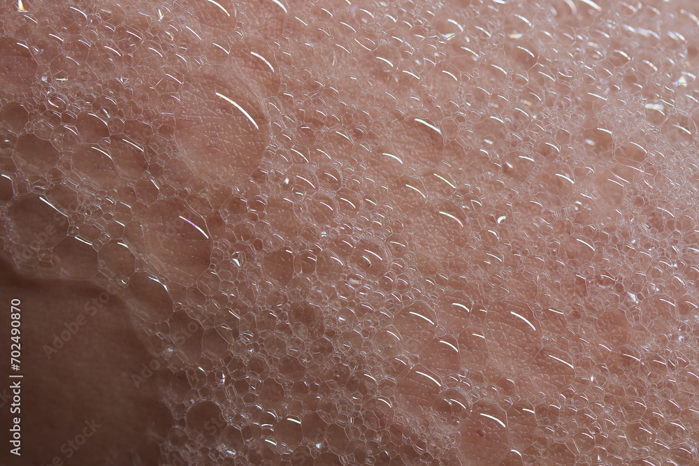 Fototapeta premium Soap foam on human skin, detailed vertical photo, foam texture on skin