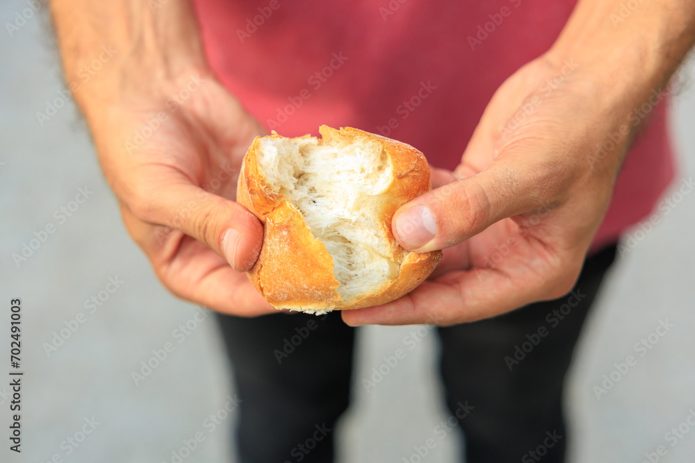 A man's hand holds a round bun, snack and fast food concept. Selective focus on hands with blurred background A man's hand holds a round bun, snack and fast food concept. Selective focus on hands with blurred background