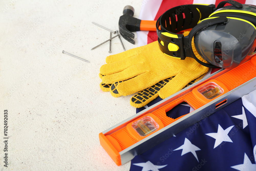 Tools, gloves, earmuffs and USA flag on white background. Labor Day celebration