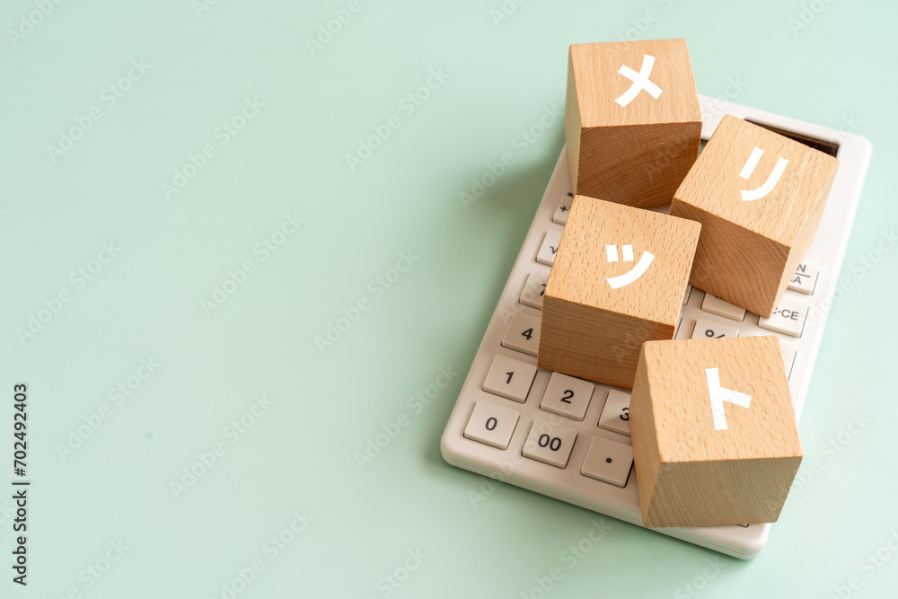 Obraz premium メリットの文字が入ったブロックと電卓