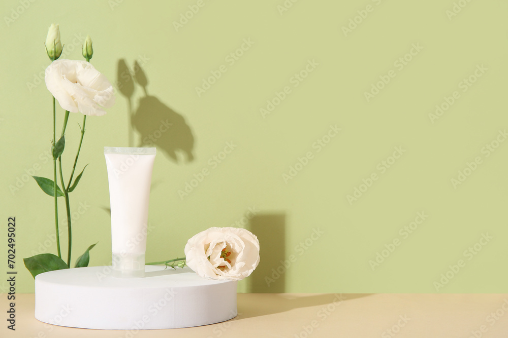 Composition with tube of cosmetic product, plaster podium and beautiful eustoma flowers on color background