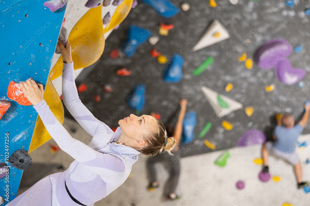 Fototapeta premium Sports woman on a climbing wall without special safety equipment