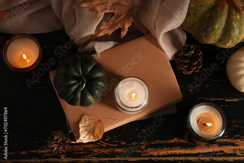 Burning candles with autumn leaves, books, pumpkins and pine cones on wooden background