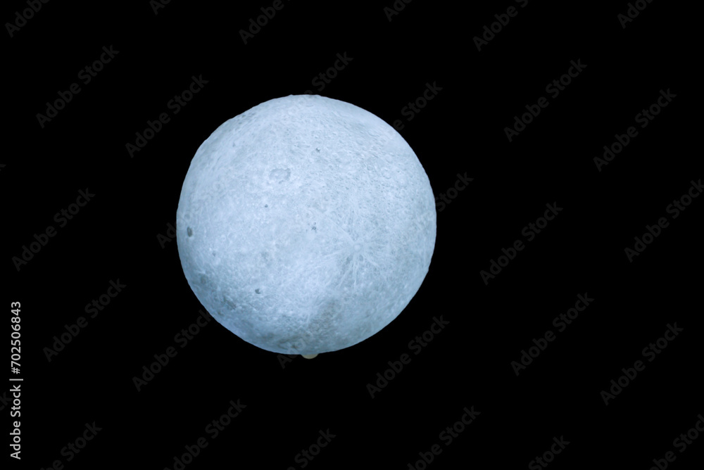 A white, full moon-shaped lamp with a rough surface. on a black background A white, full moon-shaped lamp with a rough surface. on a black background