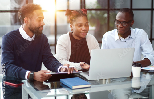 African american business team talking about strategy while looking at laptop, in office