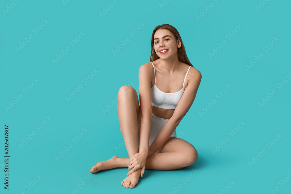 Beautiful young woman after depilation sitting on turquoise background Beautiful young woman after depilation sitting on turquoise background