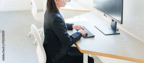 オフィスでデスクトップパソコンを使うビジネスウーマン