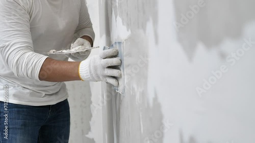 Plasterwork and wall painting preparation. Asian male applying filling drywall patch.