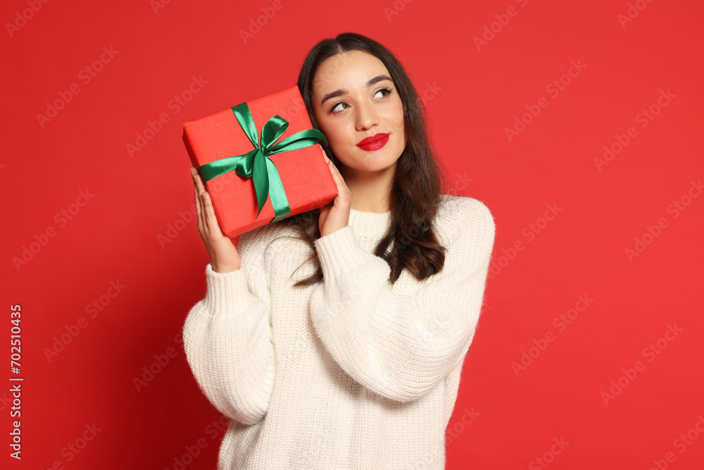 Beautiful young woman with Christmas gift on red background Beautiful young woman with Christmas gift on red background