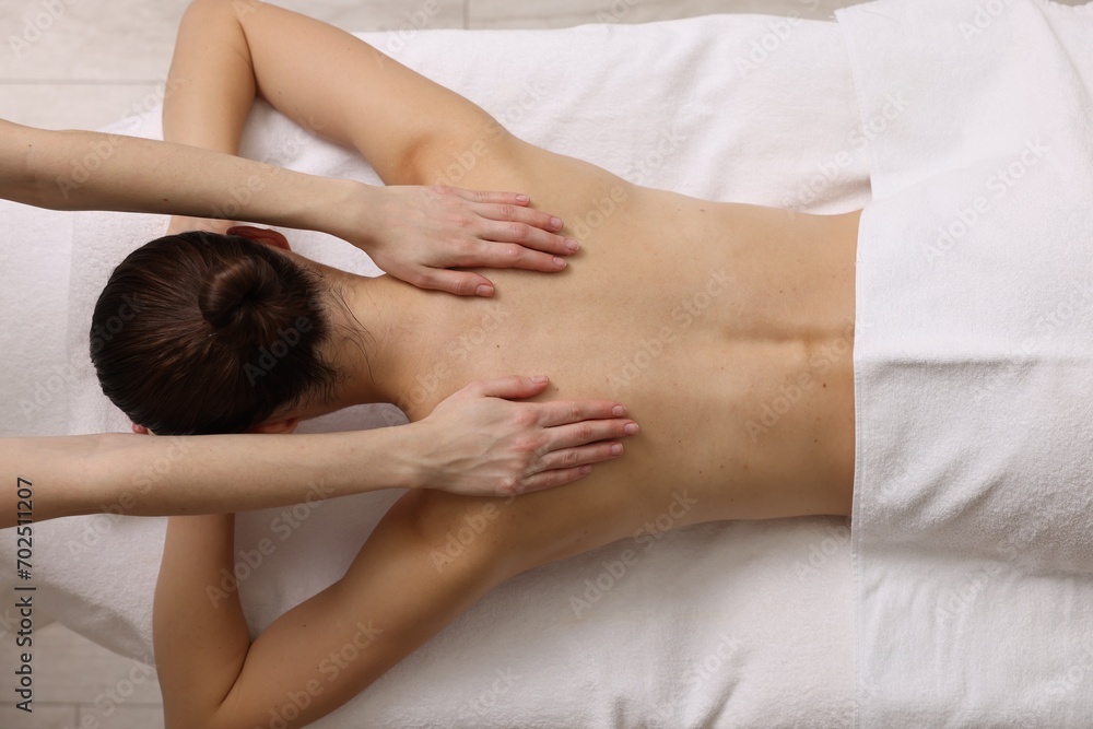 Woman receiving back massage on couch in spa salon, top view