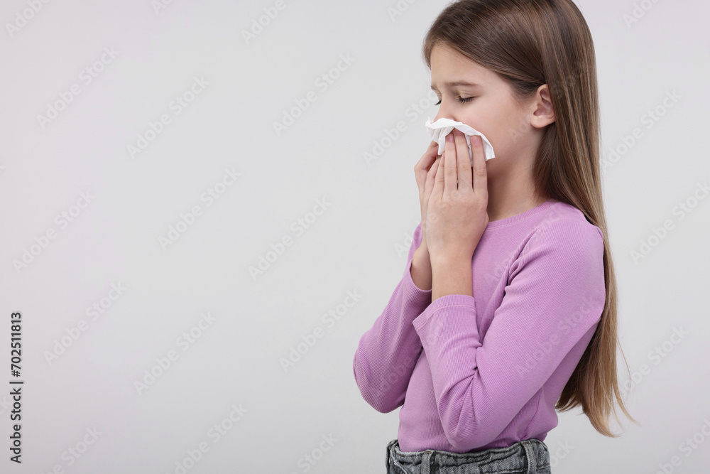 Sick girl with tissue coughing on light background, space for text