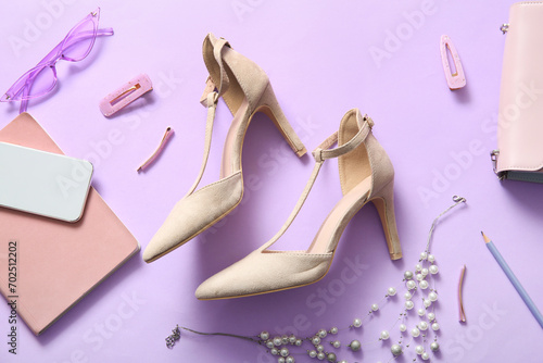Composition with stylish high heeled shoes, female accessories and mobile phone on lilac background