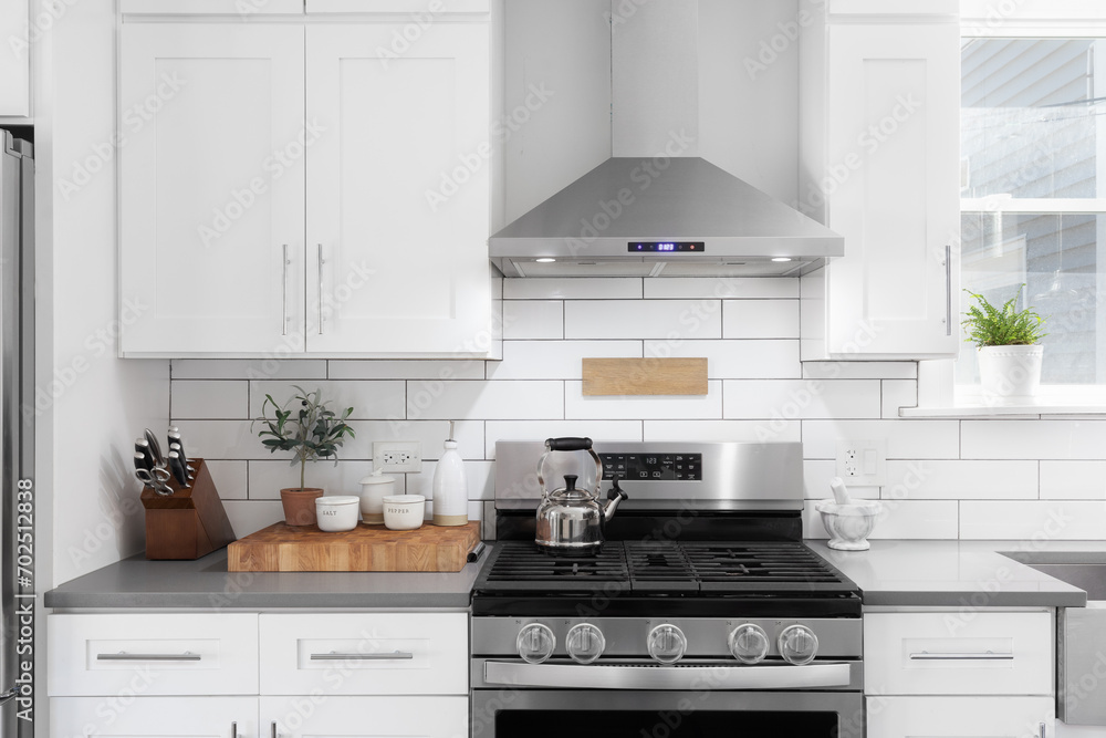 A kitchen detail shot with white cabinets, stainless steel appliances, granite countertops, and a subway tile backsplash. - obrazy, fototapety, plakaty 