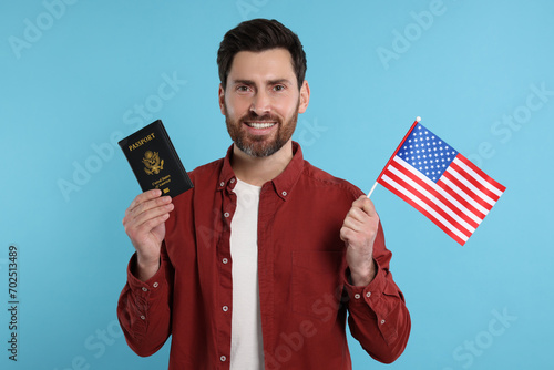 Immigration. Happy man with passport and American flag on light blue background photo