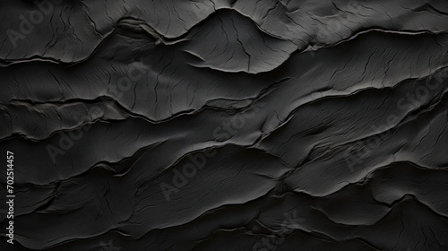 Close-up of an abstract black textured surface, with a detailed and rough aesthetic. © tashechka