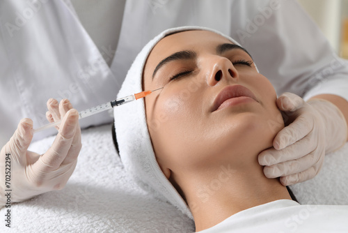 Doctor giving facial injection to young woman in clinic. Cosmetic surgery