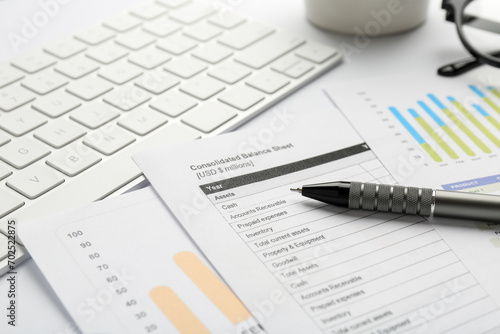 Accounting documents, pen and computer keyboard on white table, closeup