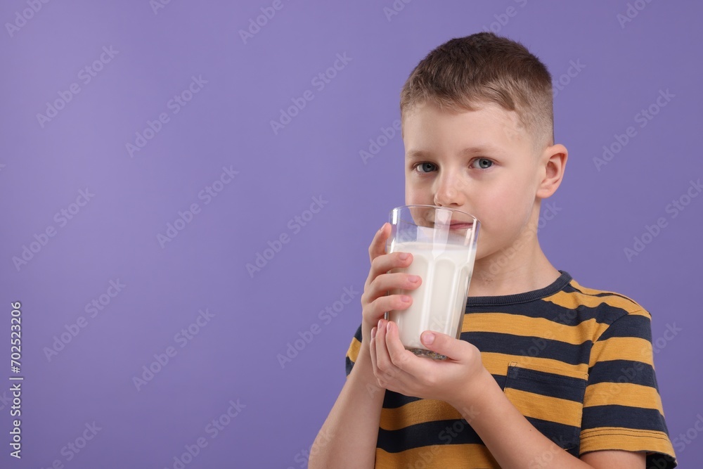 Cute boy drinking fresh milk from glass on violet background, space for text Cute boy drinking fresh milk from glass on violet background, space for text