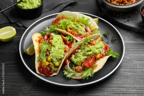Delicious tacos with guacamole, meat and vegetables on wooden table