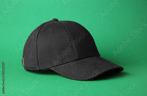 Stylish black baseball cap on green background
