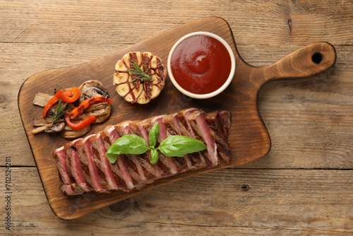 Delicious grilled beef steak with spices and tomato sauce on wooden table, top view