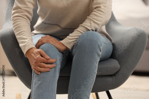 Mature woman suffering from knee pain indoors, closeup. Rheumatism symptom photo