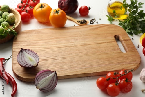 Cutting board with different vegetables on white wooden table, closeup