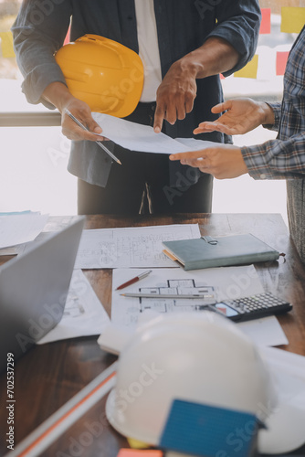 A team of construction engineers talks to managers and construction workers at the construction site. Quality inspection, work plan, home and industrial building design project