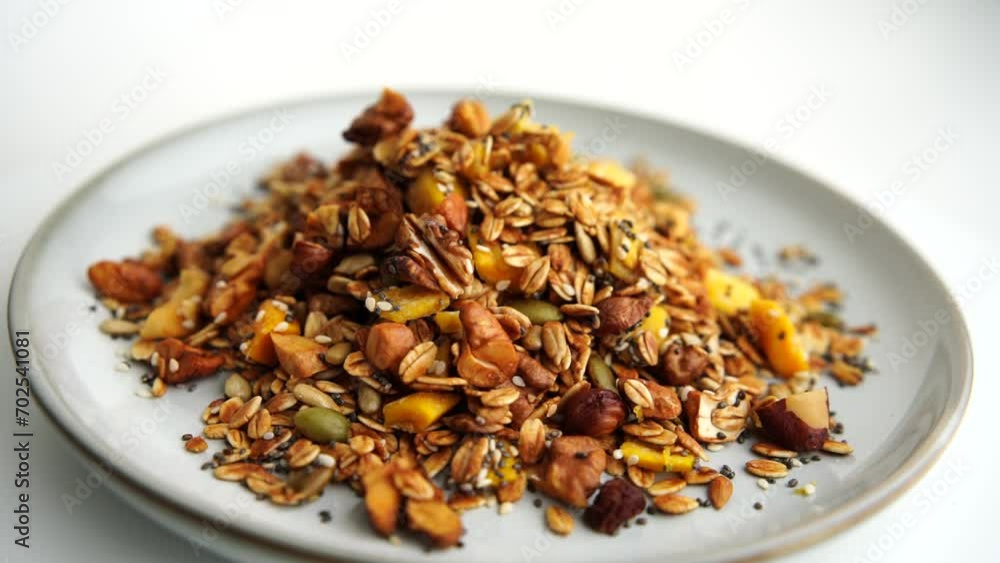 Healthy organic granola breakfast flakes with almonds, cashew nuts walnuts, hazelnuts, pumpkin seeds and cranberries circle rotation close up top view. Healthy organic granola breakfast flakes with almonds, cashew nuts walnuts, hazelnuts, pumpkin seeds and cranberries circle rotation close up top view.