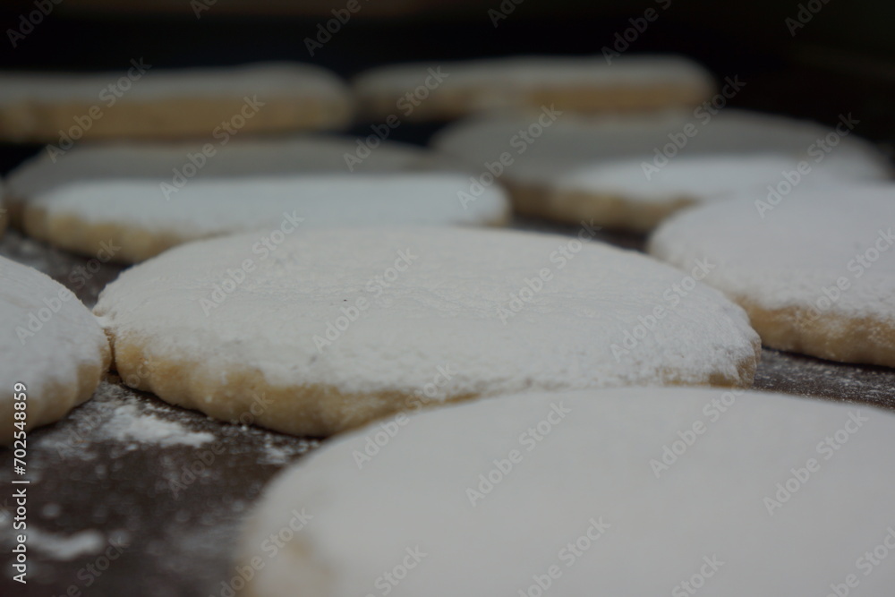 Flat Spanish polvorones with white powder, in tray, macro, well lit