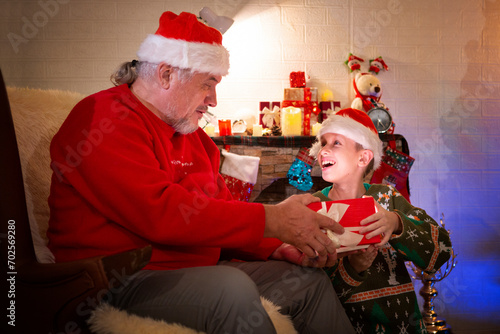 A boy is delighted to open the gift his grandfather gave him at the Christmas party.