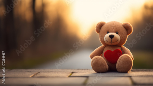 Teddy bear with red heart on sunset background. Valentine's day concept