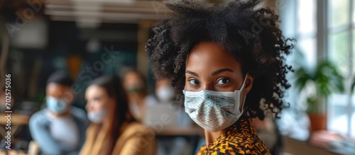 Black girl with multiethnic colleagues wearing masks in office during Covid-19 pandemic. photo