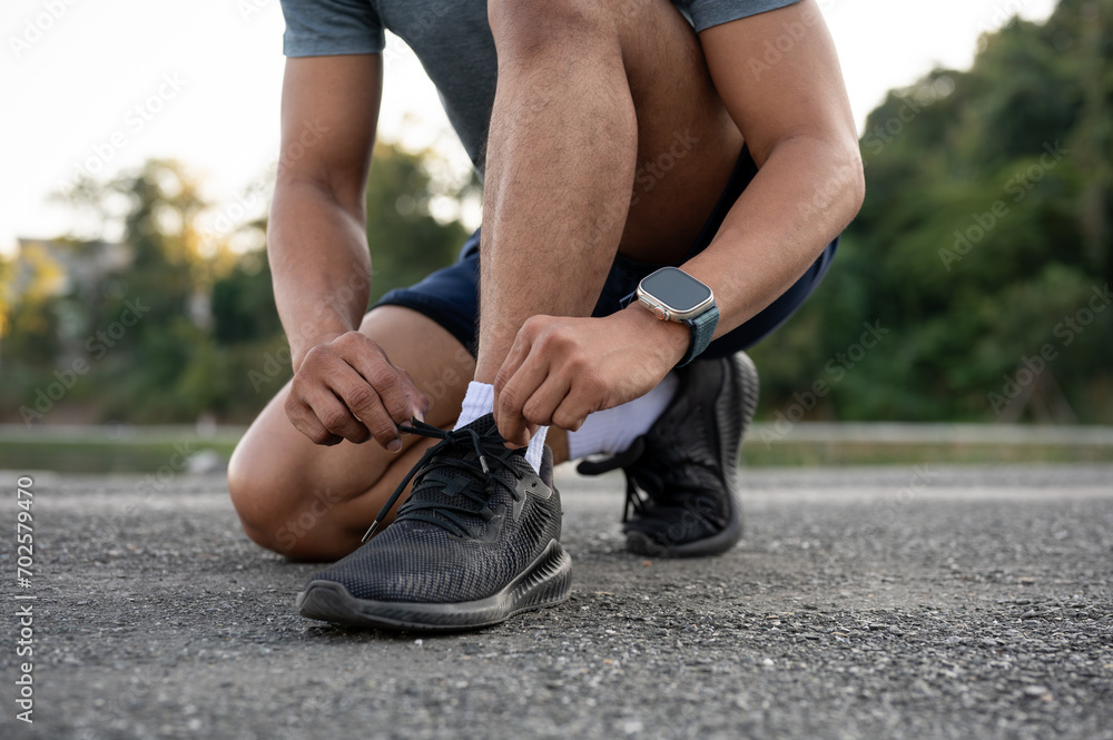 A strong, fit Asian man in sportswear is tying his shoelaces and getting ready before exercising.