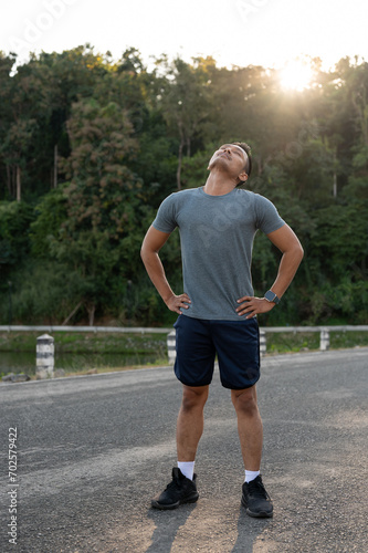A healthy, fit Asian man stretching his neck, warming up before jogging in the morning.