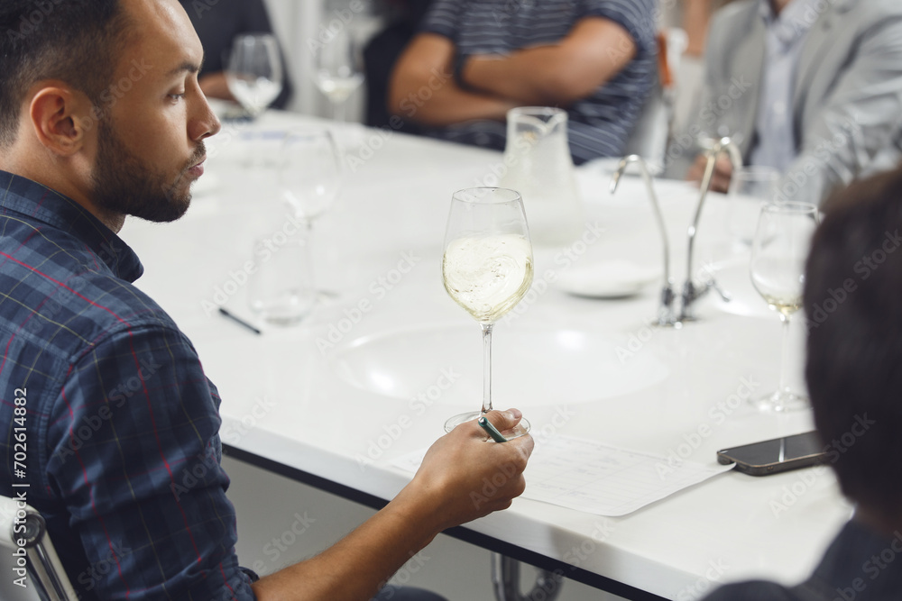 Professional looking sommelier tasting white wine from glass, analysing its taste, color, smell and acidity level. Wine expert studies wine geographic and area on winemaking lecture. Professional looking sommelier tasting white wine from glass, analysing its taste, color, smell and acidity level. Wine expert studies wine geographic and area on winemaking lecture.