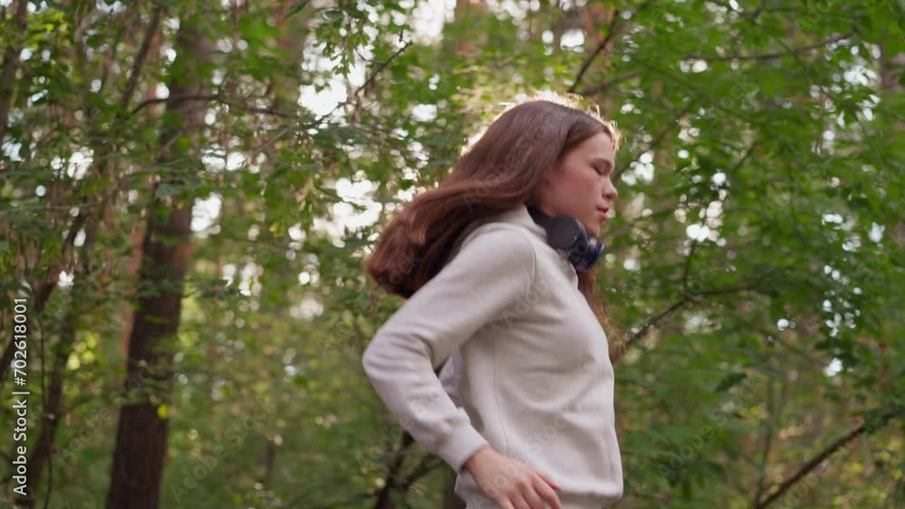 Female athlete jumps in place with intensity in forest. Woman performs physical exercises breathing deeply in nature. Active fitness training to get toned body Female athlete jumps in place with intensity in forest. Woman performs physical exercises breathing deeply in nature. Active fitness training to get toned body