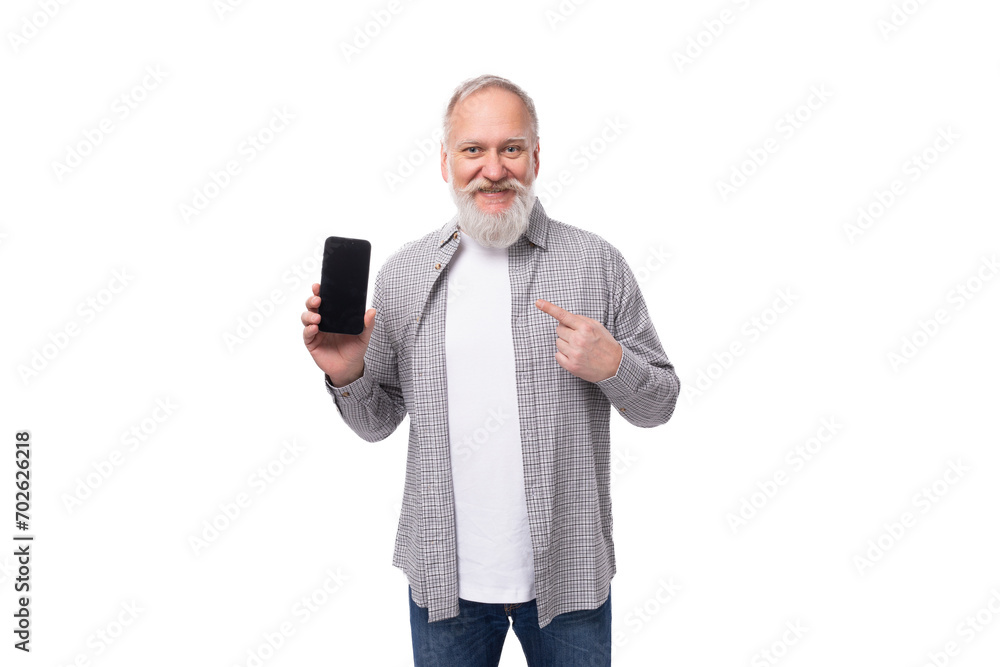 Φωτογραφία cute grandfather with white beard and mustache dressed in a striped shirt over a t-shirt shows a smartphone screen with a mockup
