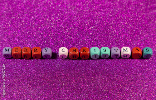 Merry Christmas written with wooden cubic beads on a purple background. Image for decoration, ornament