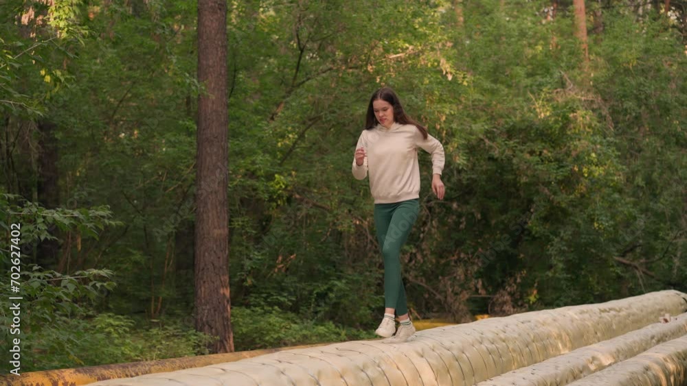 Woman runs on heat pipeline surface in city park. Female athlete engages in challenging sprint to improve coordination of movements. Professional training Woman runs on heat pipeline surface in city park. Female athlete engages in challenging sprint to improve coordination of movements. Professional training