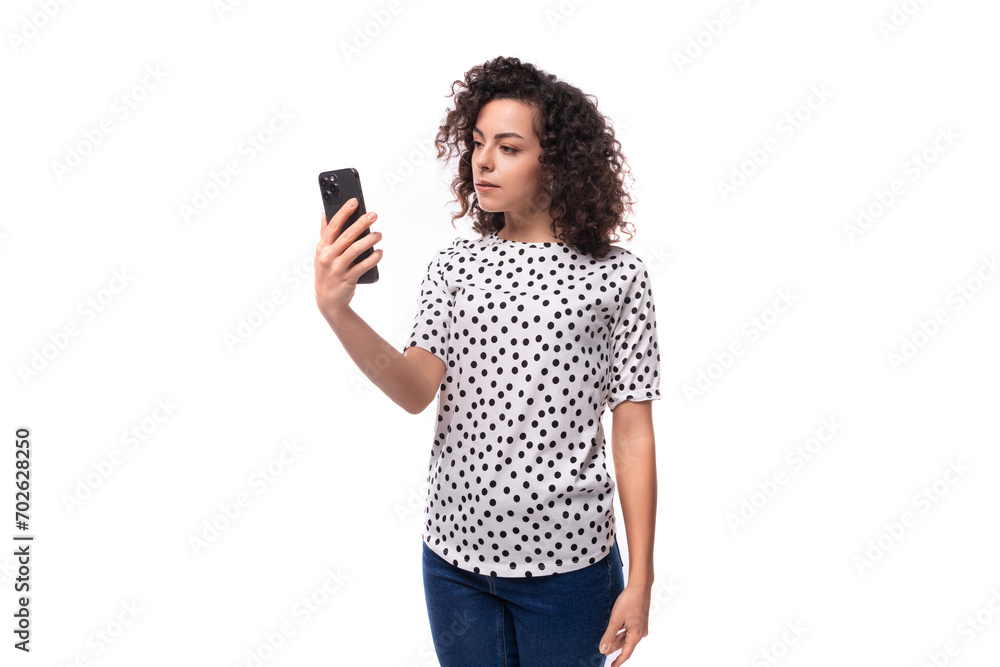 cute curly young brunette with shoulder-length hair dressed in a short-sleeved shirt makes a selfie on the phone cute curly young brunette with shoulder-length hair dressed in a short-sleeved shirt makes a selfie on the phone