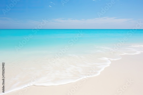 Serene beach with gentle waves and a gradient of blue in the sky and sea